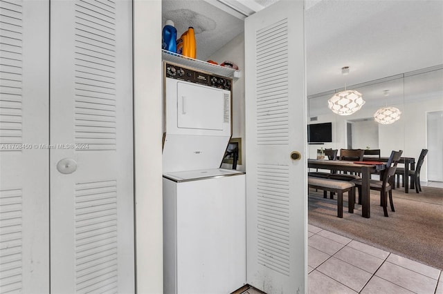 laundry room featuring a textured ceiling, light colored carpet, and stacked washer and dryer