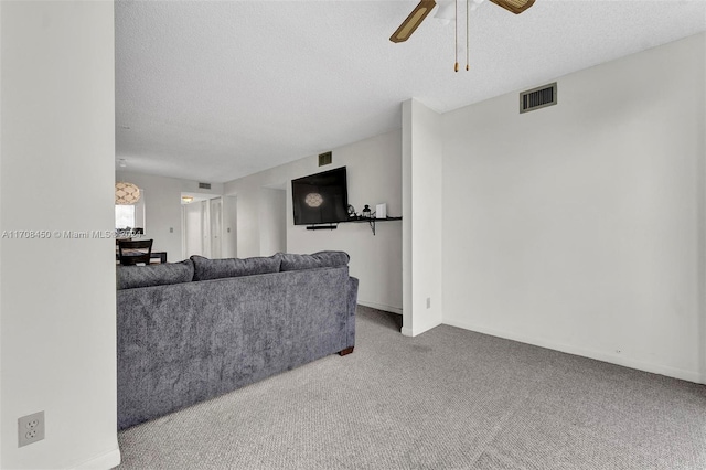 living room with ceiling fan, carpet floors, and a textured ceiling