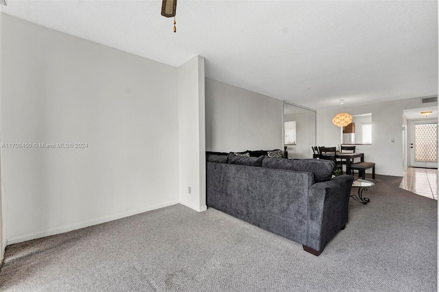 carpeted living room with ceiling fan and a textured ceiling