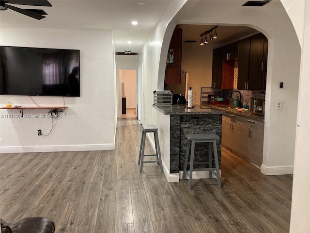 bar with ceiling fan, sink, rail lighting, dark wood-type flooring, and backsplash