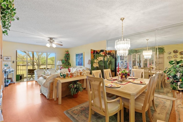 dining space with a textured ceiling, light hardwood / wood-style floors, and ceiling fan with notable chandelier