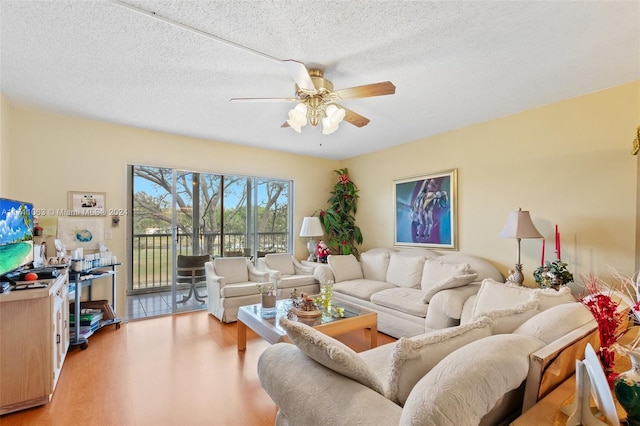 living room with ceiling fan, a textured ceiling, and light wood-type flooring