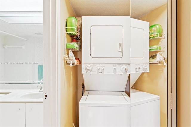 washroom featuring a textured ceiling, stacked washer and dryer, and sink