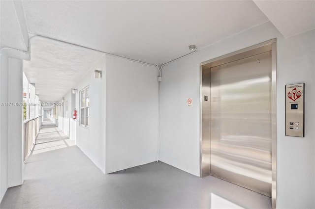 hallway featuring elevator and concrete floors