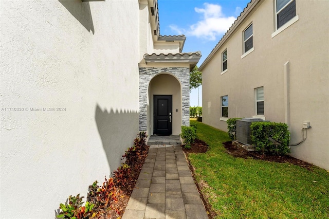 property entrance with central AC unit and a lawn