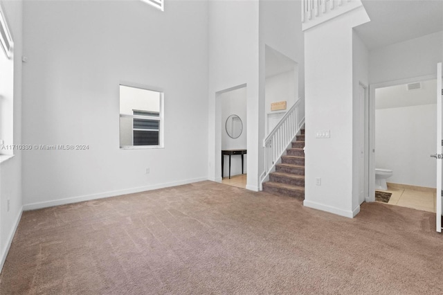 interior space with light colored carpet and a high ceiling