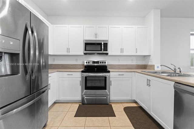 kitchen with white cabinetry, sink, light tile patterned floors, and stainless steel appliances