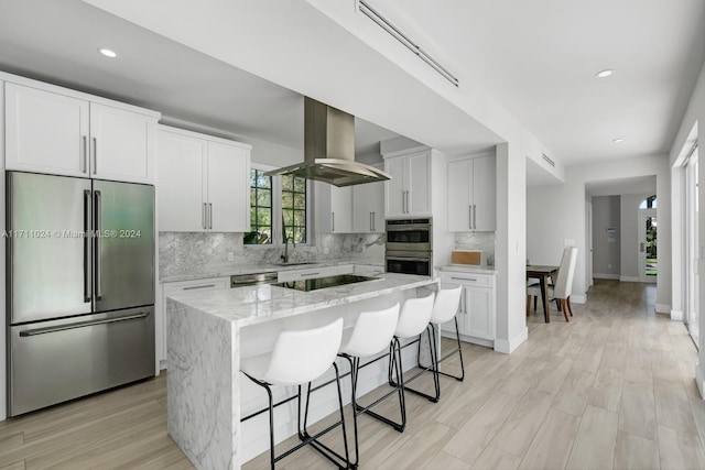 kitchen featuring white cabinets, light hardwood / wood-style flooring, appliances with stainless steel finishes, a kitchen island, and island exhaust hood