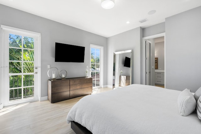 bedroom featuring access to outside, connected bathroom, multiple windows, and light wood-type flooring