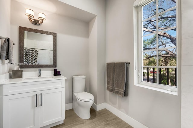 bathroom featuring a wealth of natural light, vanity, wood-type flooring, and toilet