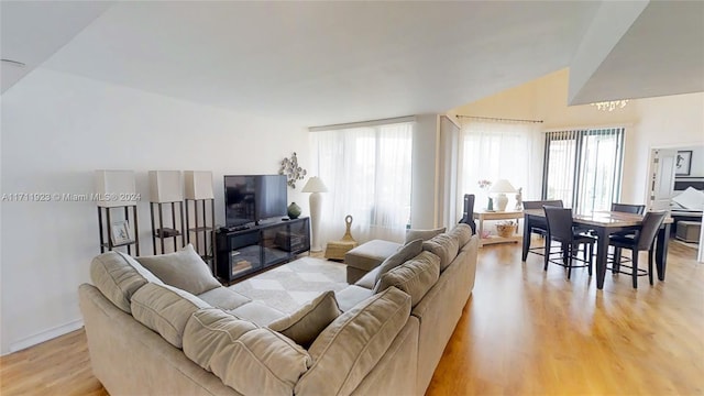 living room featuring light hardwood / wood-style floors, vaulted ceiling, and a wealth of natural light