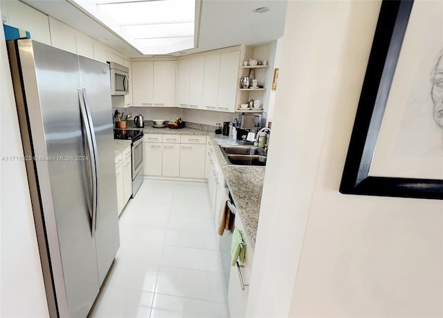 kitchen featuring sink, light stone countertops, light tile patterned floors, white cabinetry, and stainless steel appliances