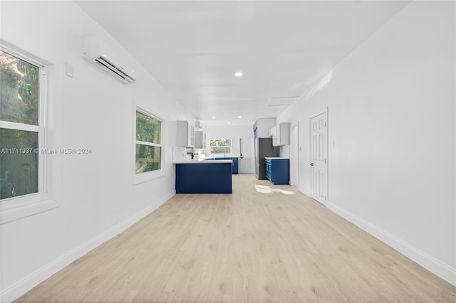 unfurnished living room featuring light hardwood / wood-style floors and a wall mounted air conditioner