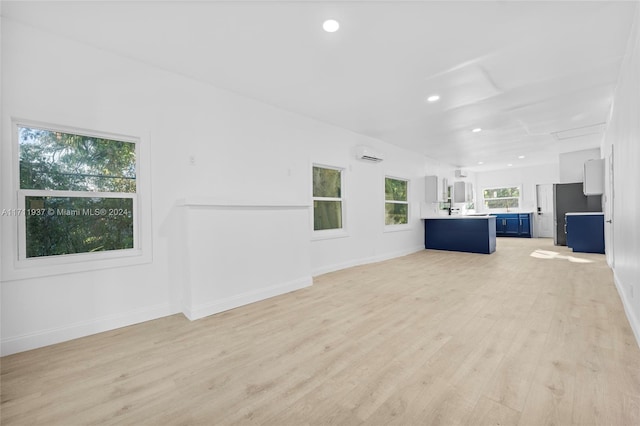 unfurnished living room featuring light hardwood / wood-style floors and an AC wall unit