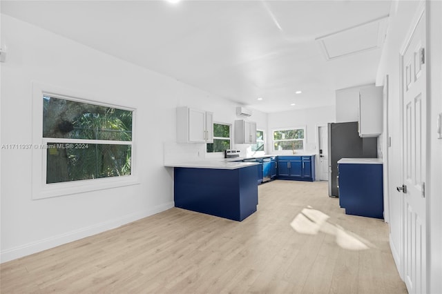 kitchen featuring white cabinets, a kitchen breakfast bar, blue cabinetry, light hardwood / wood-style floors, and kitchen peninsula