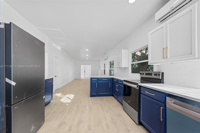 kitchen with stainless steel appliances, blue cabinets, a wall mounted AC, light hardwood / wood-style flooring, and white cabinetry