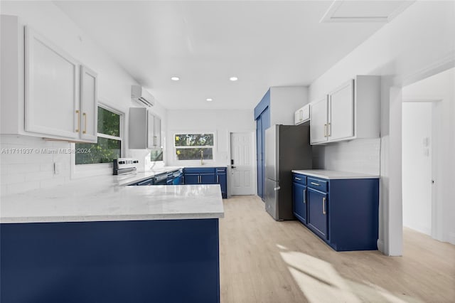 kitchen with white cabinets, light hardwood / wood-style floors, kitchen peninsula, and blue cabinets