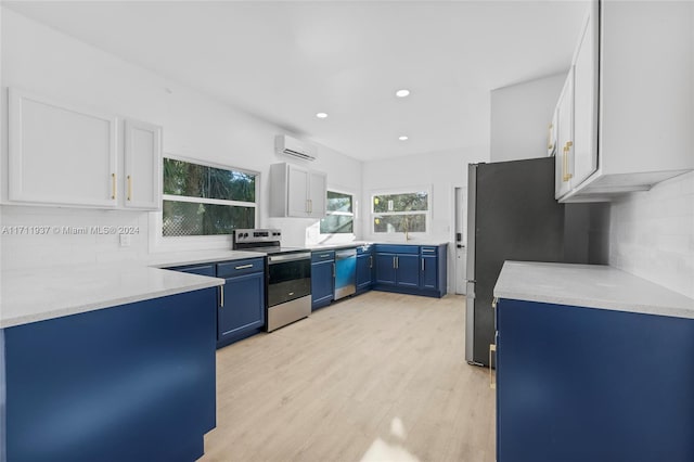 kitchen featuring appliances with stainless steel finishes, blue cabinetry, light hardwood / wood-style flooring, an AC wall unit, and white cabinets