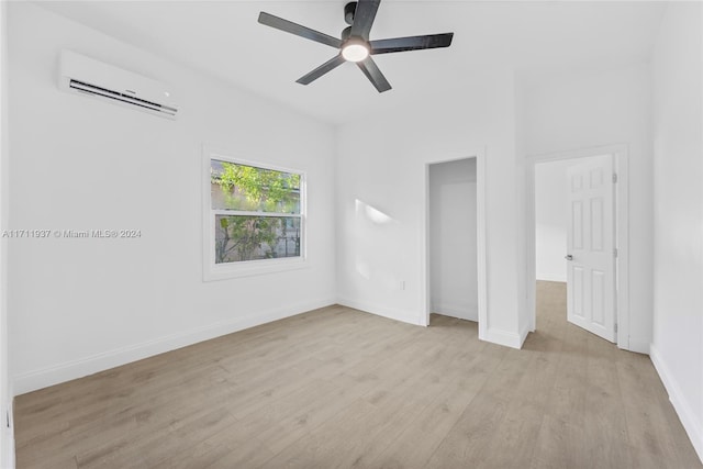 unfurnished bedroom with light hardwood / wood-style floors, a wall mounted AC, and ceiling fan