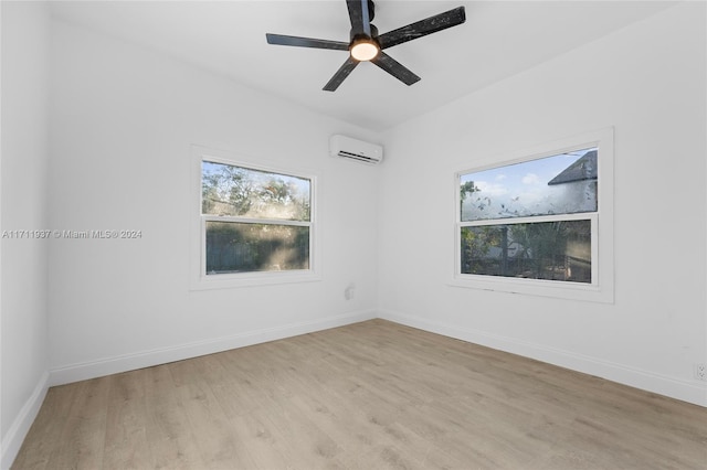 spare room with a wall mounted air conditioner, ceiling fan, and light hardwood / wood-style floors