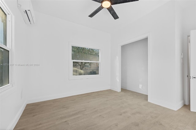 empty room featuring a wall mounted air conditioner, ceiling fan, and light hardwood / wood-style flooring