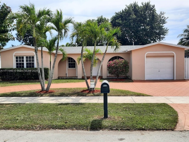 single story home with stucco siding, decorative driveway, a front yard, and an attached garage