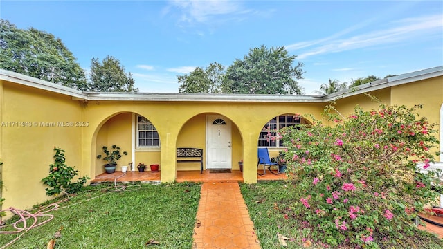 property entrance with a yard and stucco siding