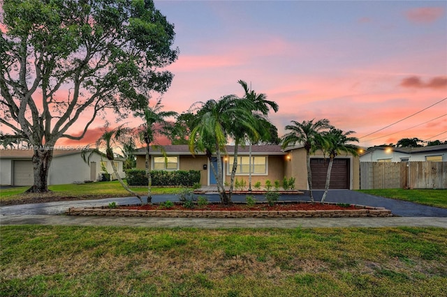 ranch-style house featuring a garage and a yard