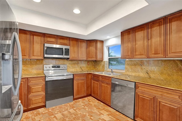 kitchen with sink, light stone countertops, stainless steel appliances, and tasteful backsplash