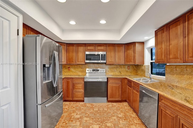 kitchen featuring appliances with stainless steel finishes, tasteful backsplash, light stone counters, and sink