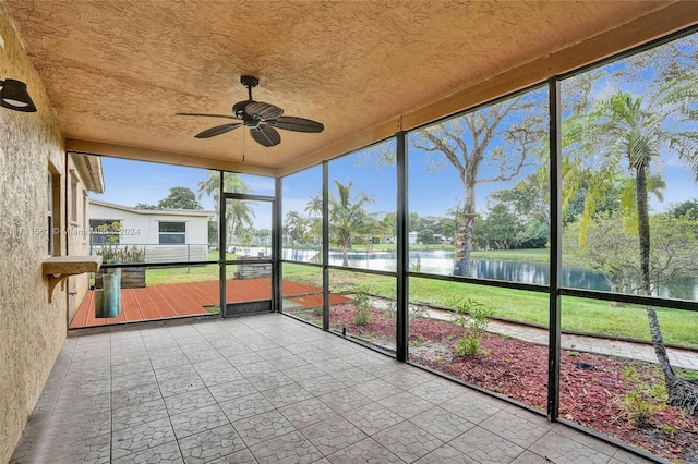 unfurnished sunroom featuring ceiling fan, plenty of natural light, and a water view