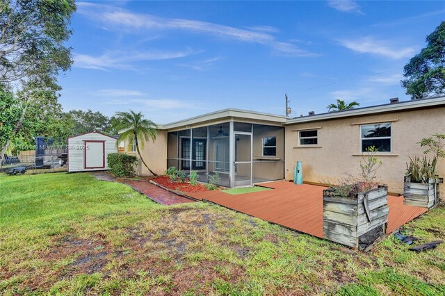 rear view of house with a wooden deck, a sunroom, a yard, and a storage unit