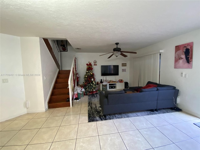 living room with ceiling fan, light tile patterned flooring, and a textured ceiling