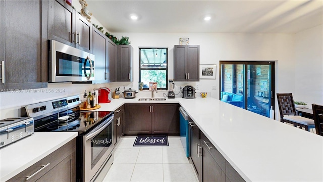 kitchen featuring light tile patterned floors, dark brown cabinetry, stainless steel appliances, and sink