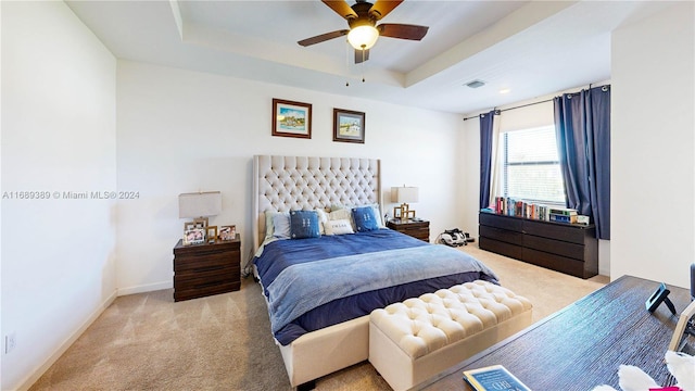 bedroom featuring ceiling fan, a raised ceiling, and light colored carpet