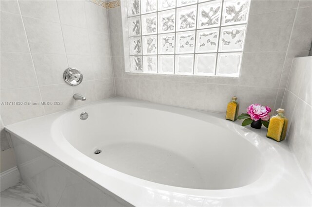 bathroom featuring a relaxing tiled tub and a healthy amount of sunlight