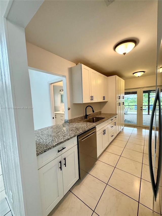 kitchen with french doors, stainless steel dishwasher, light tile patterned floors, stone counters, and white cabinetry