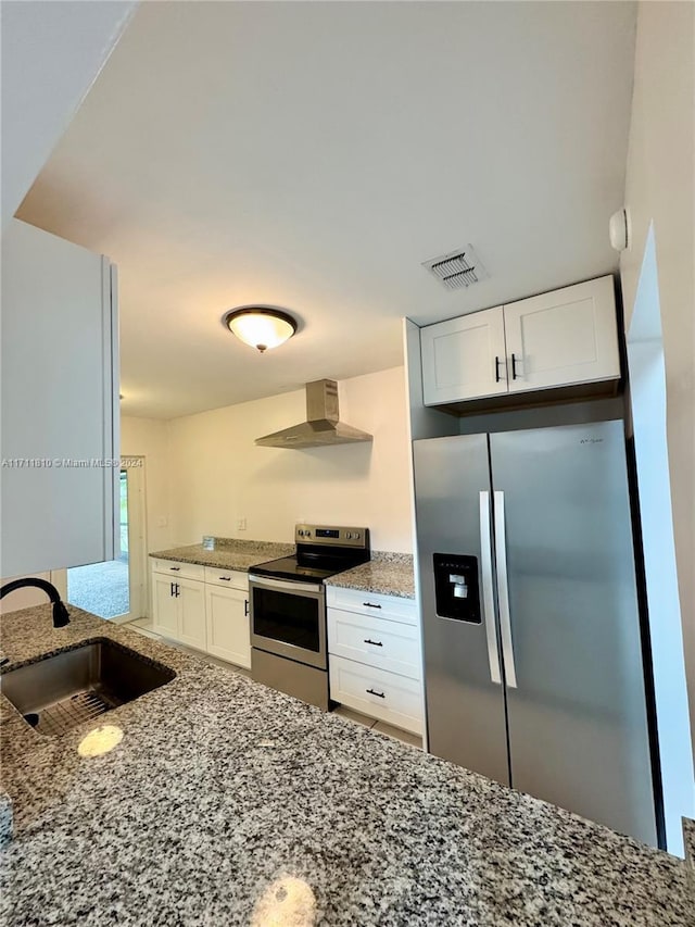 kitchen with white cabinets, sink, wall chimney exhaust hood, appliances with stainless steel finishes, and light stone counters