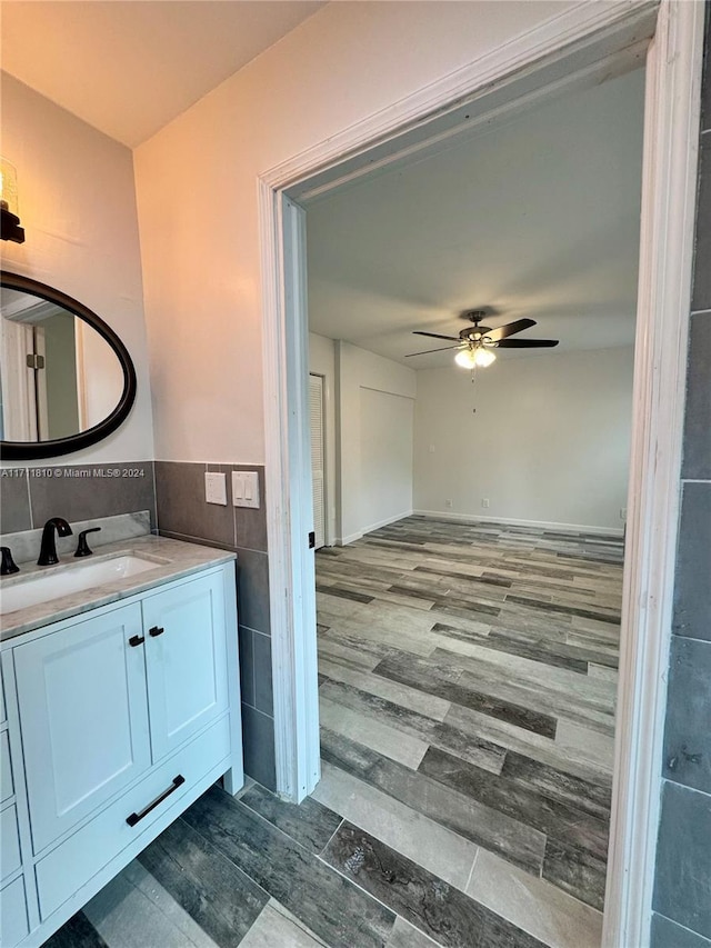 bathroom featuring hardwood / wood-style flooring, vanity, ceiling fan, and tile walls