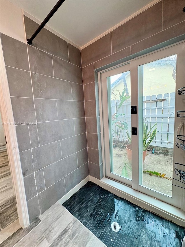 doorway to outside with hardwood / wood-style flooring, crown molding, and tile walls