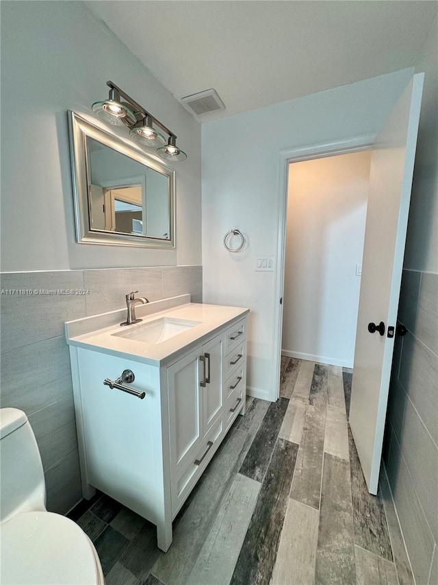 bathroom featuring hardwood / wood-style floors, vanity, toilet, and tile walls