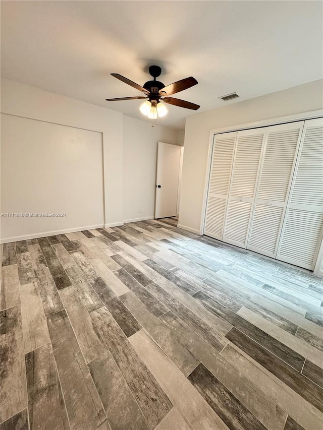 unfurnished bedroom featuring wood-type flooring, a closet, and ceiling fan