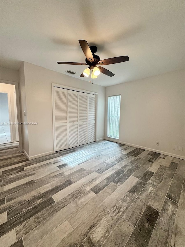 unfurnished bedroom with ceiling fan, dark wood-type flooring, and a closet