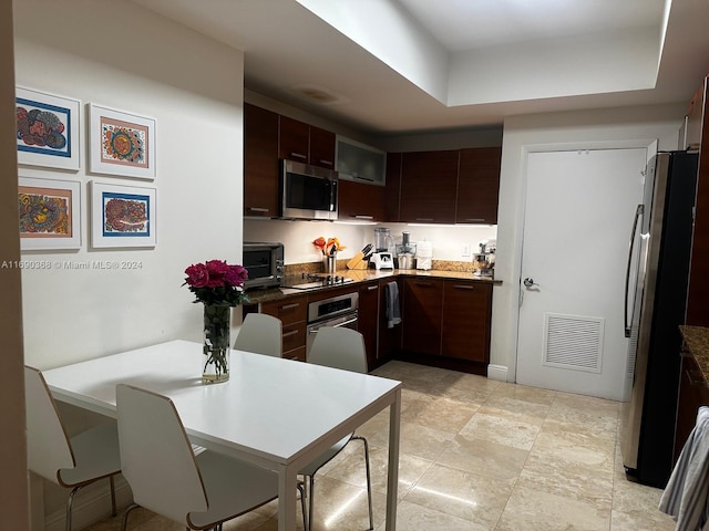 kitchen with dark brown cabinets, a raised ceiling, and appliances with stainless steel finishes