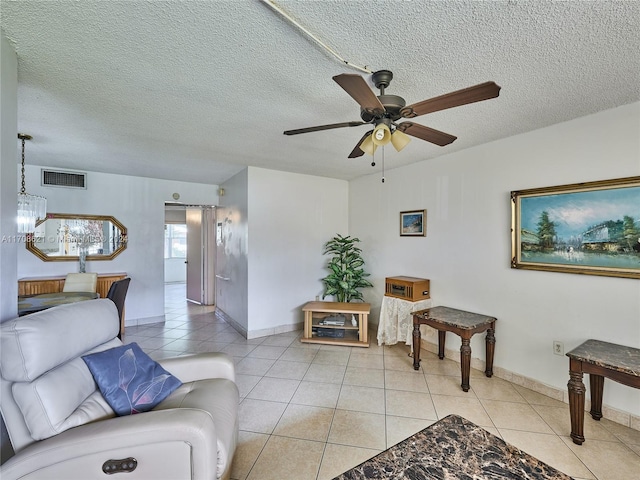 tiled living room featuring ceiling fan with notable chandelier and a textured ceiling