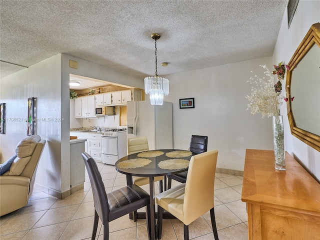 dining space featuring a textured ceiling, a notable chandelier, and light tile patterned flooring