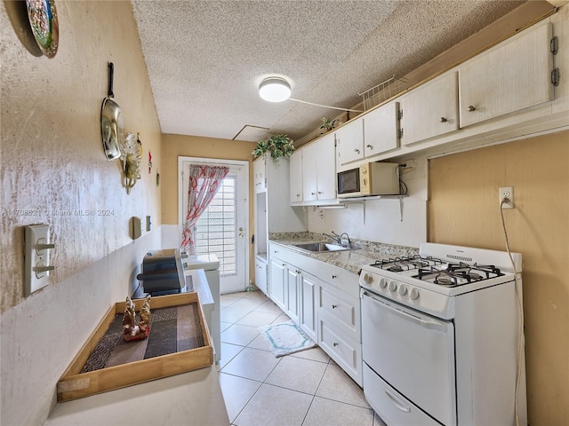 kitchen with light stone countertops, white gas range, a textured ceiling, sink, and light tile patterned floors