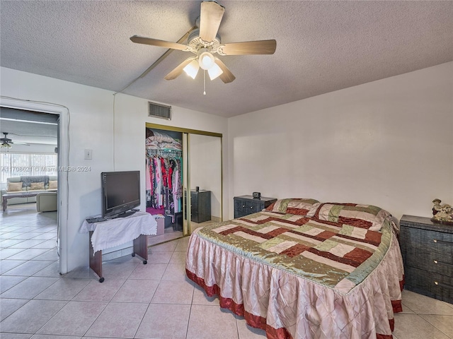 bedroom featuring ceiling fan, light tile patterned floors, a textured ceiling, and a closet