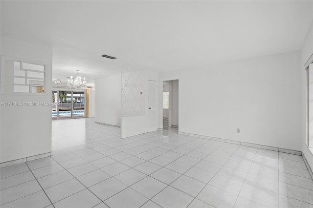 empty room with light tile patterned floors and a chandelier