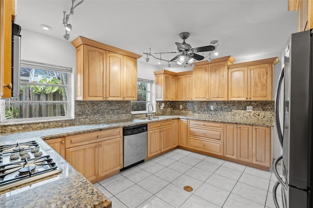 kitchen with light stone countertops, tasteful backsplash, stainless steel appliances, ceiling fan, and sink